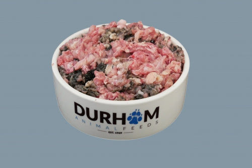 A cream coloured bowl with Durham Animal Feeds written in blue & black, containing raw Chicken Mince with dark coloured tripe pieces mixed in.