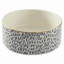 A deep dog bowl, with a gold rim, cream inside, and a black & cream animal print on the outside.