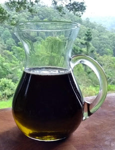 A clear glass jar in a window, filled with Nature's Grub natural hemp oil.