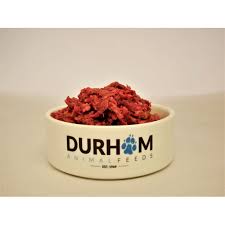 A cream coloured bowl with Durham Animal Feeds written on it in blue and black, containing raw pork mince.