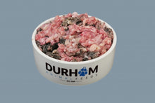 Load image into Gallery viewer, A white bowl with Durham Animal Feeds written on it in blue and black, containing raw turkey and tripe mince, against a pale blue background.
